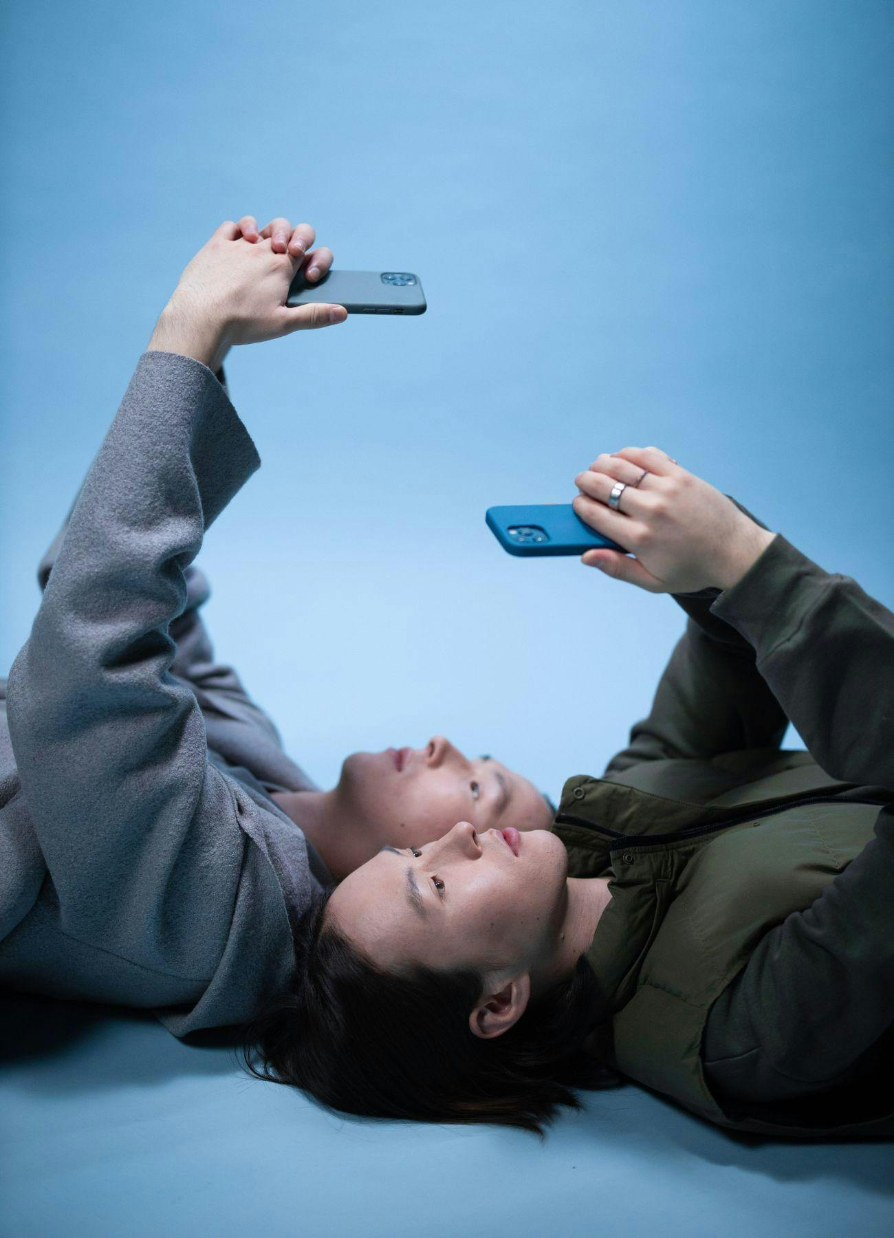 Jongeren liggend op de grond en houden hun smartphones boven hun hoofd.