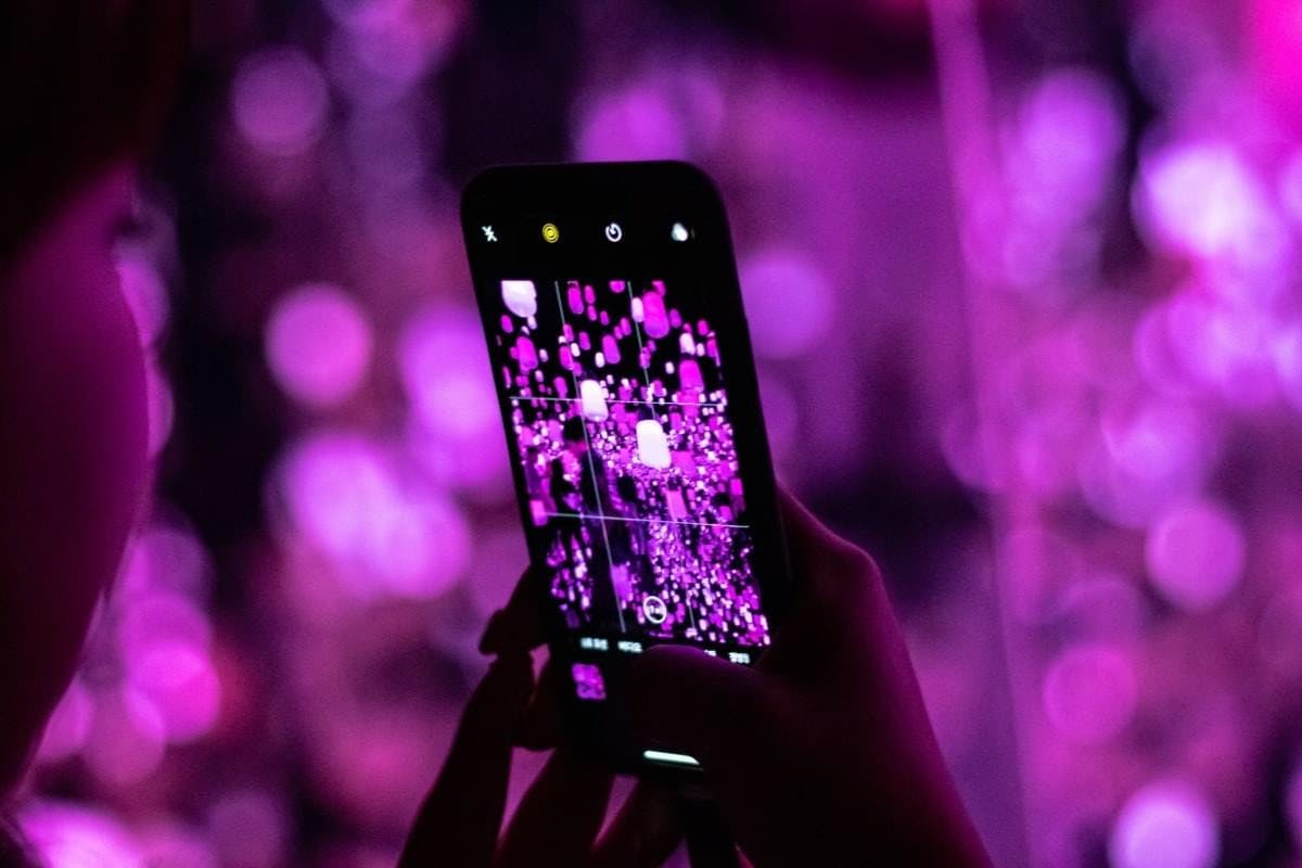 Een jong meisje maakt een foto op haar telefoon van de roze verlichting.