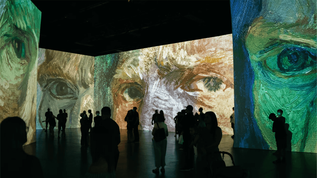 Mensen lopen door een expositieruimte waarin digitaal uitvergrote werken van Van Gogh te zien zijn