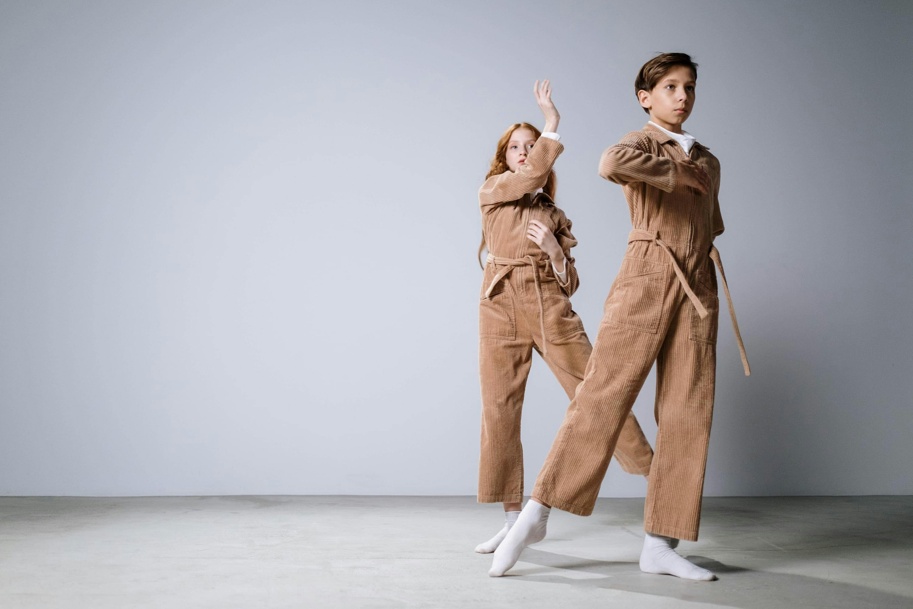 Twee jonge dansers in beige broekpakken.