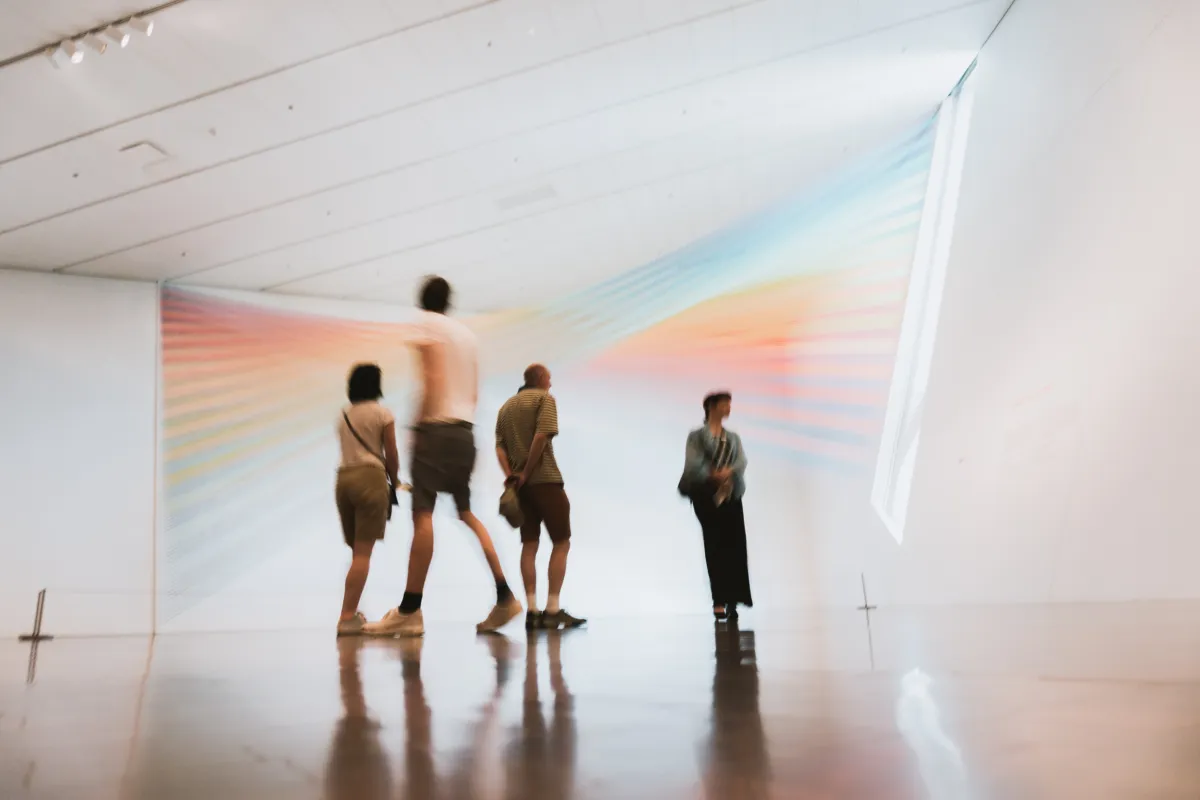 People in a museum with a light projection on the background
