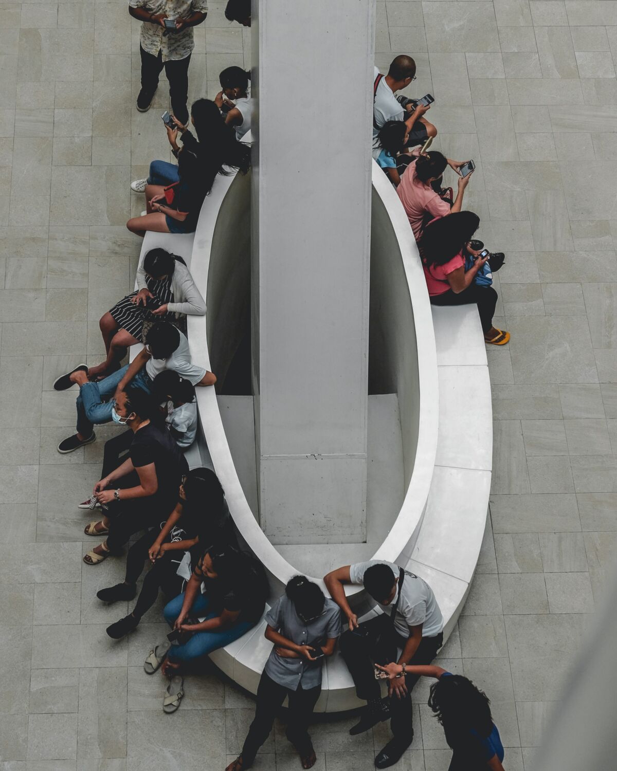 Groep jongeren (Gen Z) zit op een bankje, ze kijken allemaal naar hun smartphones. Dit is het publiek van de toekomst.
