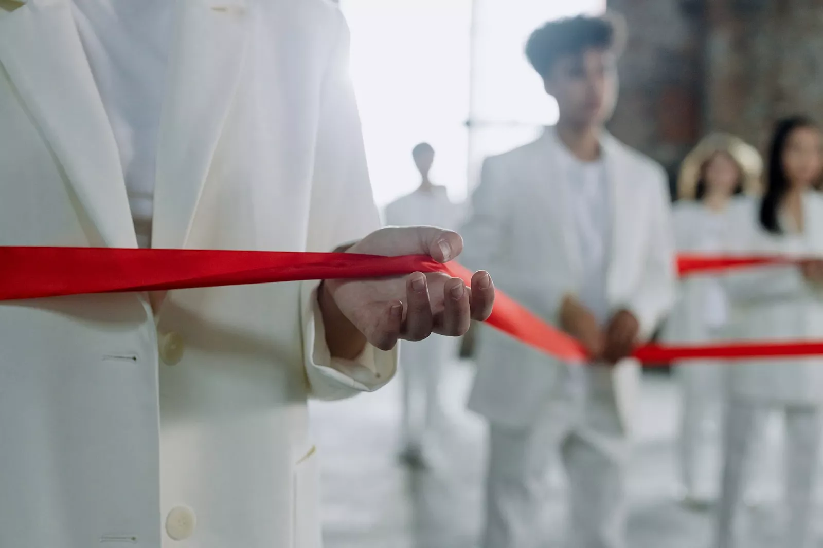 Mensen in witte kleding houden samen rood lint vast