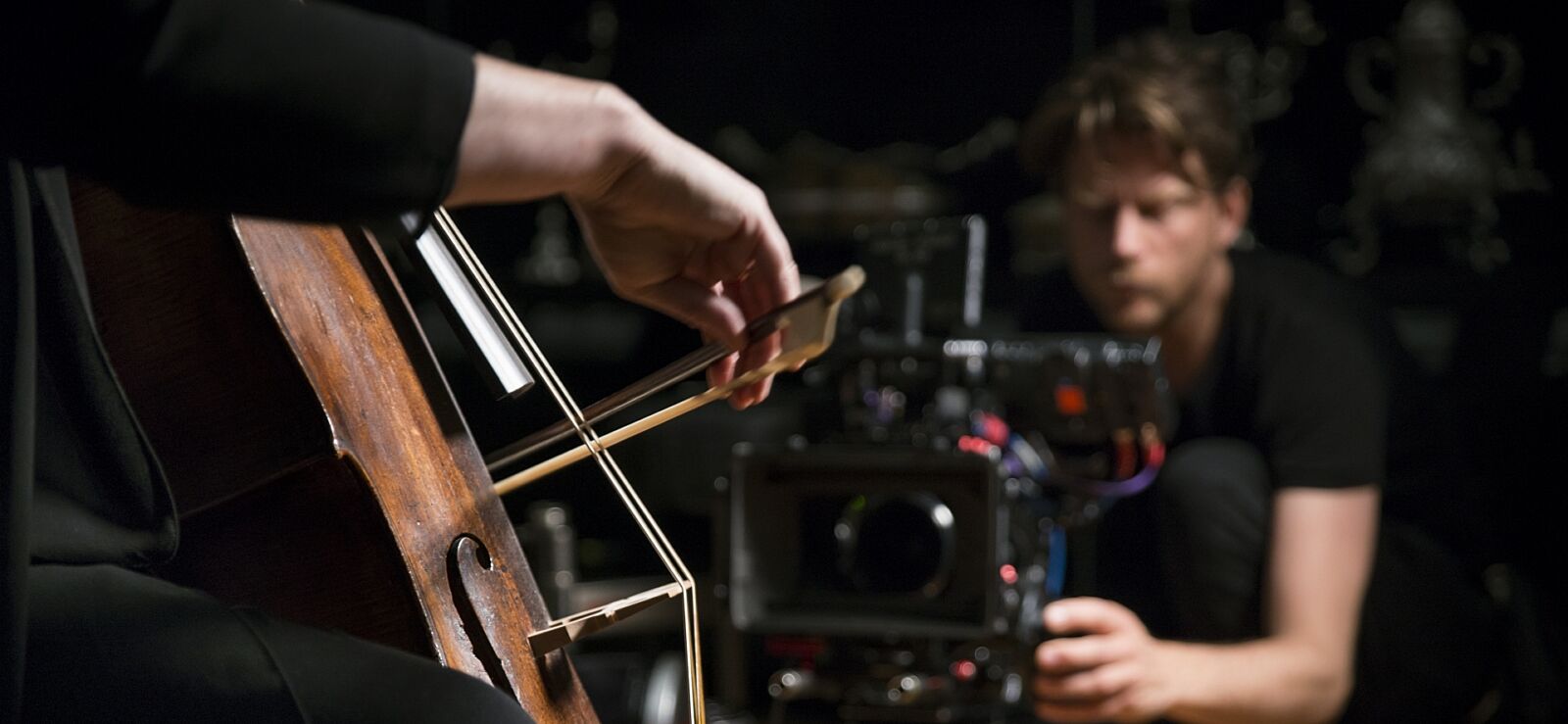 Een man met filmcamera die cellist filmt