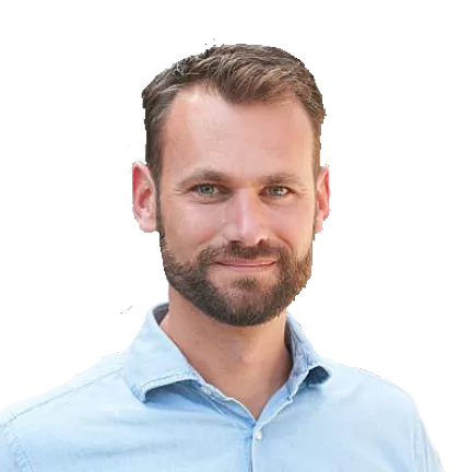 Portret van een man met kort haar en een baard in een lichtblauw overhemd.
