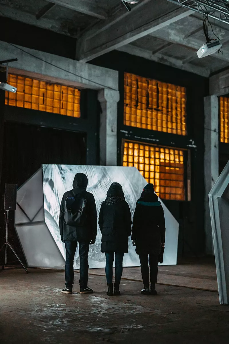 Drie mensen staan met hun rug naar de camera en bekijken een object.